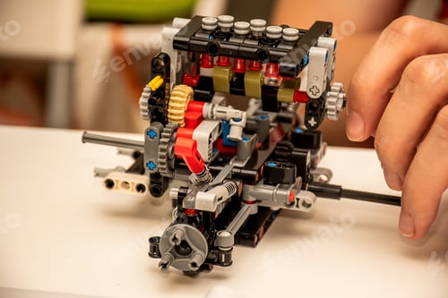Preview: Hands making a piece of complex machinery from plastic pieces blocks constructor details