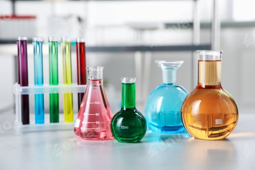 Preview: Different laboratory glassware with color liquids on light table indoors