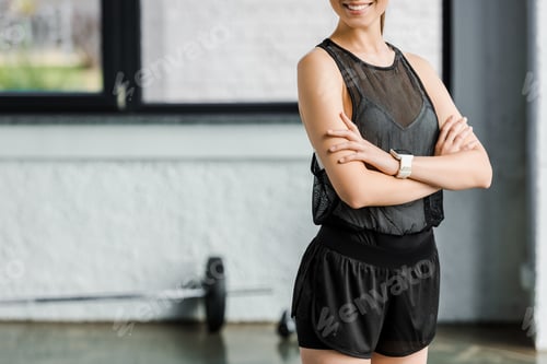 Preview: midsection of smiling sportswoman in black at gym