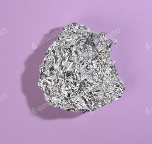 Preview: Crumpled piece of gray foil with shadow on purple