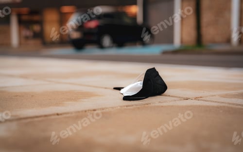 Preview: Used medical face mask discard on floor on blur car at parking lot and building in city.