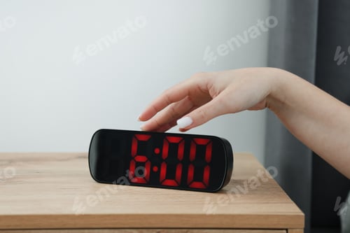 Preview: Woman turning off digital alarm clock on bedside table indoors, closeup