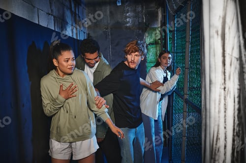 Preview: scared interracial friends walking through secret passage in quest room, adventure and mystery