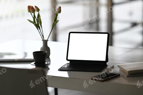 Preview: A computer tablet with a white blank screen is putting on a working desk.