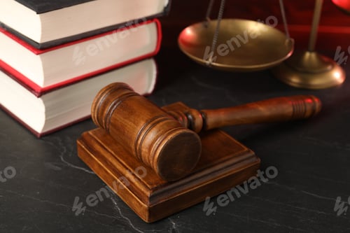Preview: Wooden gavel, scales and stack of books on dark textured table, closeup