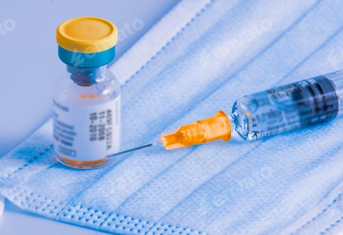 Preview: Closeup shot of a syringe and a vial on a surgical mask - the concept of a virus