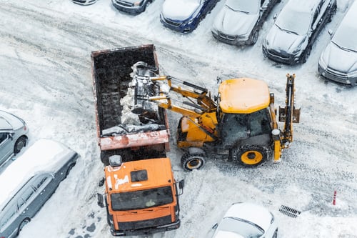 Preview: Tractor loader machine uploading dirty snow into dump truck. Cleaning city street, removing snow and