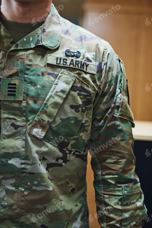 Preview: Cropped shot of a soldier wearing camouflage fatigues with a badge attached to velcro on his chest