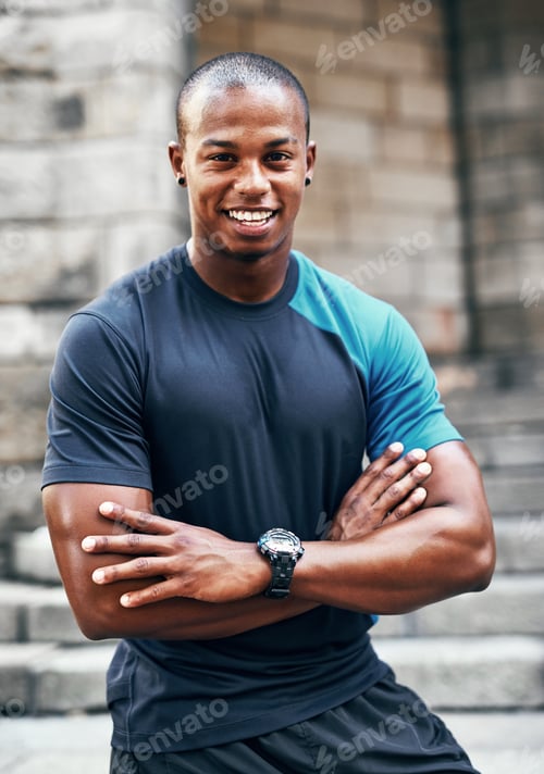Preview: Portrait of a handsome young sportsman posing with his arms folded outdoors
