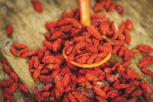 Preview: Goji Berries in a spoon on a wooden board.