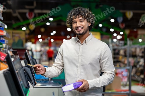 Preview: Smiling man using self-service checkout at a grocery store with card