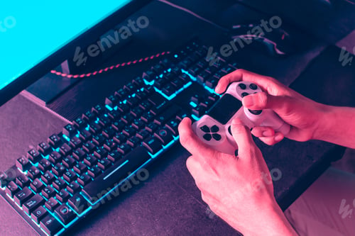 Preview: hands holding a joystick to play a video game in front of a monitor.