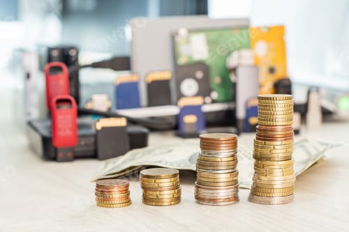 Preview: Stacks of coins rising in height against a backdrop of computer storage devices