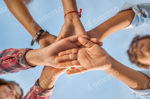 Preview: Unity concept. Bottom view of little children putting their hands together indoors