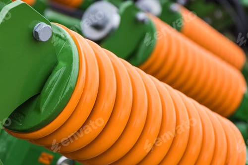 Preview: Orange hard spring made of steel. Part of big industrial or agricultural machine