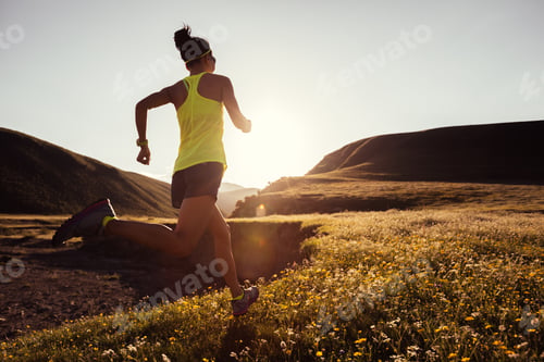 Preview: Young fitness woman trail runner running on sunset grassland