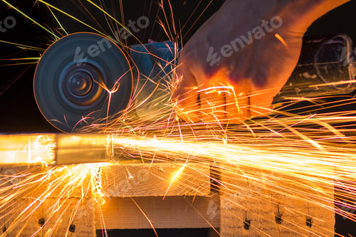 Preview: Close-up of worker hands cutting metal with grinder. Sparks while grinding iron. Low depth of focus
