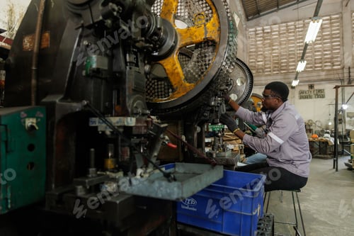 Preview: african black male worker working in heavy metal industry factory punching stamping steel machine