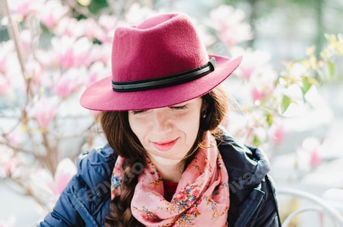 Preview: A beautiful woman smiling in front of blooming magnolia tree