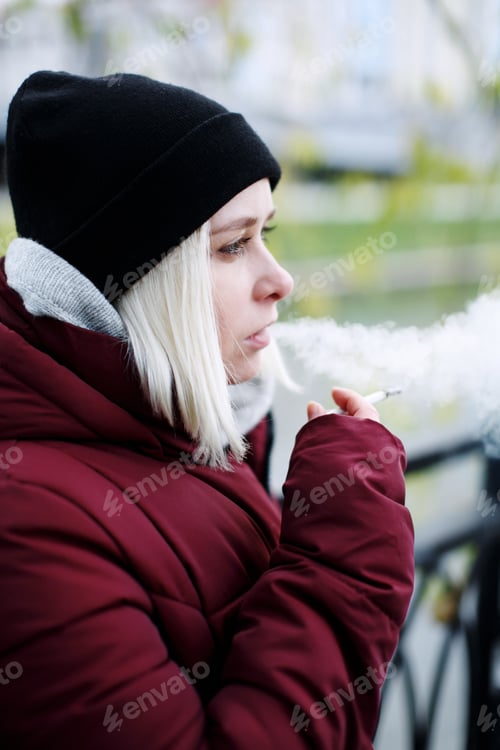 Preview: Young thoughtful hipster millennial woman smoking a cigarette outdoors