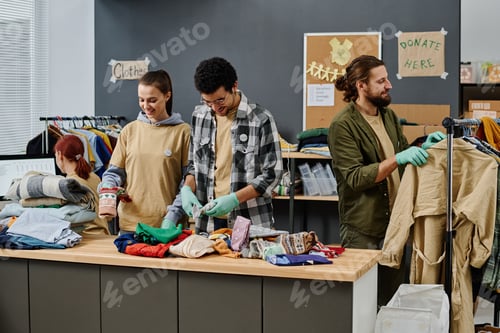 Preview: Group of young volunteers sorting clothes and choosing items for people in need