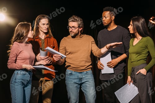 Preview: multiethnic actors and actresses rehearsing with theater director on stage