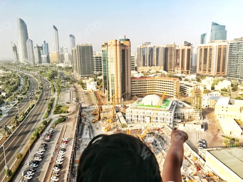 Preview: Child from behind points at the city view from his apartment building