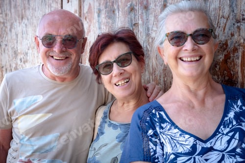 Preview: Happy group of three people friends enjoying outdoor excursion standing against a wooden door