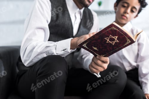 Preview: cropped view of jewish father and son reading tanakh in apartment