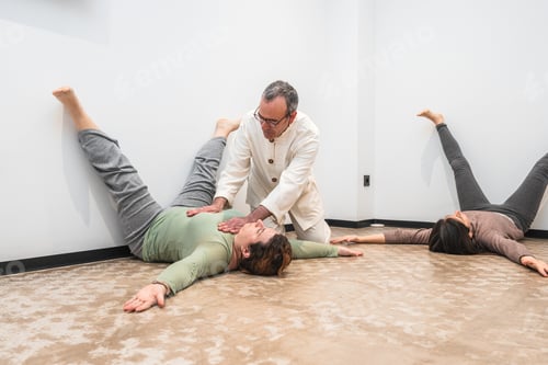 Preview: Yoga instructor assisting senior woman in legs-up-the-wall pose during a wellness session.