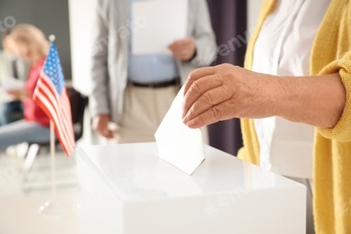Preview: Elderly woman putting ballot paper into box at polling station, closeup