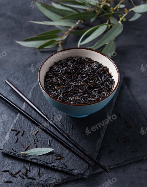 Preview: black rice in two blue bowl on a slate Board on a black background