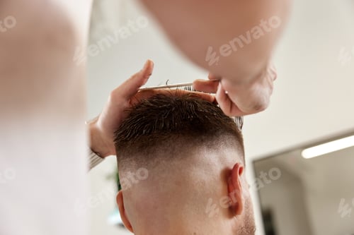 Preview: hairdresser does haircut for man using comb and grooming scissors