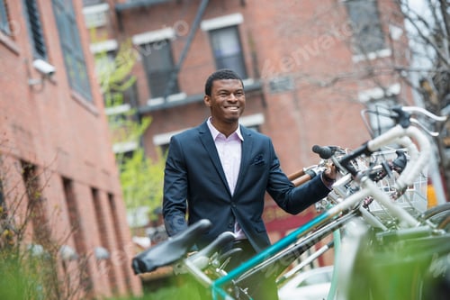 Preview: City life in spring. A man in a blue suit, by a bicycle rack in a city park.