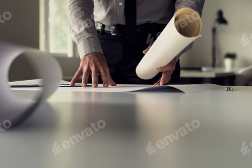 Preview: Businessman working on blueprints in an office in a low angle view