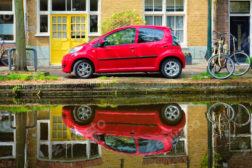 Preview: Red car on canal embankment in street of Delft. Delft, Netherlands