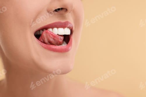 Preview: Woman with beautiful lips licking her teeth on beige background, closeup. Space for text