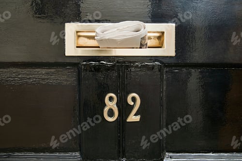 Preview: Close up of Newspaper in letterbox with number eighty two