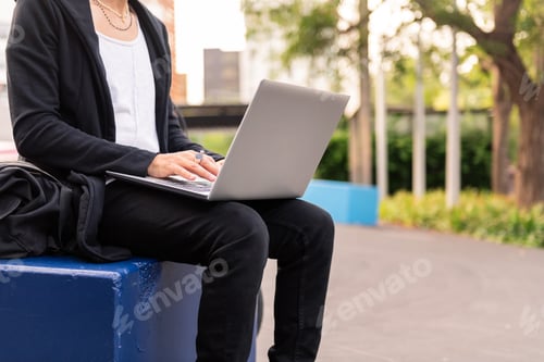 Preview: unrecognizable student working on laptop outdoors