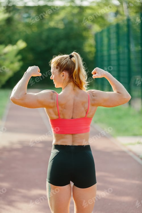Preview: Strong woman flexing muscles on outdoor track