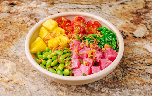 Preview: Fresh poke bowl with tuna, pineapple, and vegetables on a marble countertop
