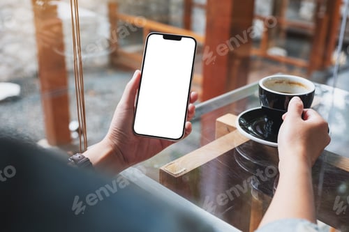 Preview: Mockup image of hands holding mobile phone with blank desktop screen while drinking coffee