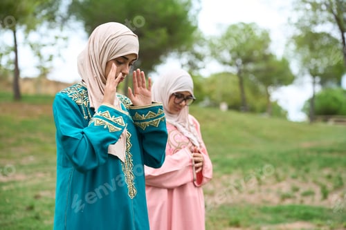 Preview: Muslim women praying outdoors practicing islamic faith