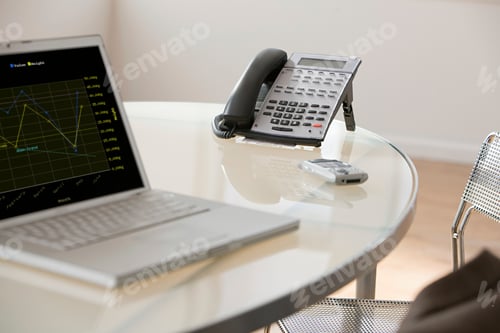 Preview: A professional workplace setup with a laptop and telephone on a clear desk.