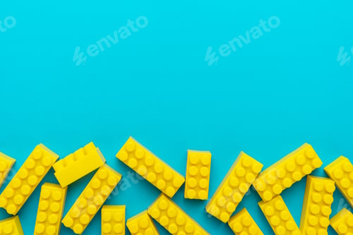 Preview: Yellow Plastic Building Blocks on Turquoise Blue Background with Copy Space