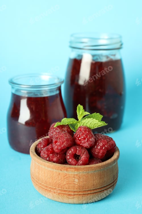 Preview: Jars of raspberry jam with ingredients on blue background