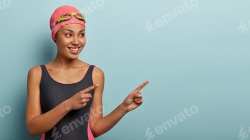 Preview: Lovely satisfied female vacationist take break after swimming, points to side, shows free space for