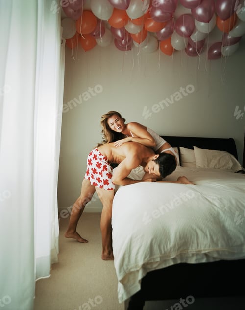 Preview: Smiling couple wrestling on bed