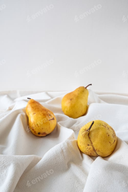Preview: Ripe pears on white color tablecloth.