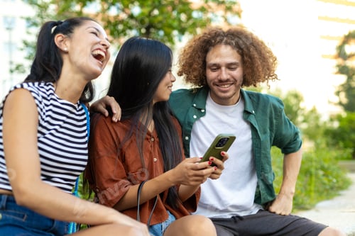 Preview: Group of students laughing together while using a smartphone outdoors